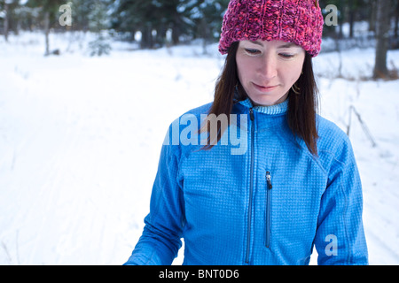 Eine Frau Langlaufski auf einem Trail im Wald. Stockfoto