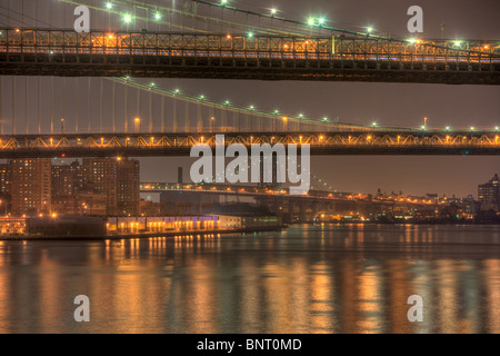 Brooklyn, Manhattan und Williamsburg Brücken auf den East River in der Nacht in New York City. Stockfoto