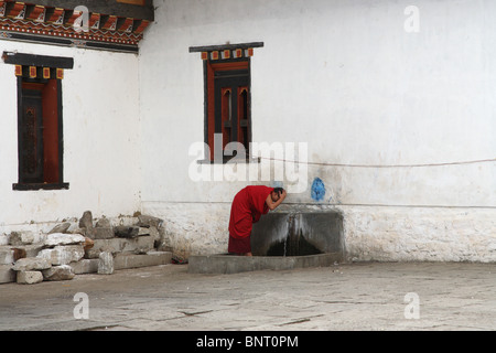 Ein Mönch, waschen sich in der Ecke eines Hofes in Klosters Tashichho Dzong in Thimpu, Bhutan. Stockfoto