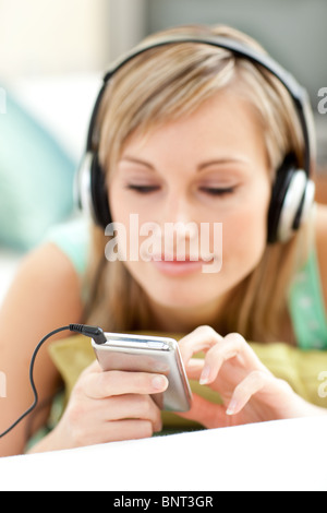 Hübsche junge Frau auf einem Sofa liegend Musik hören Stockfoto