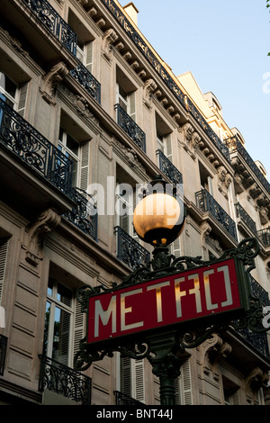 Paris Metro Schild mit reich verzierten Lampe oben in einer Paris Straße mit typischen Parisienne Gebäude im Hintergrund Stockfoto