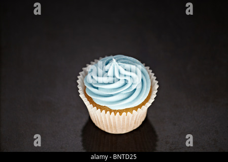 Cupcakes mit blauen Sahnehäubchen auf einer schwarzen Marmor Oberfläche Stockfoto