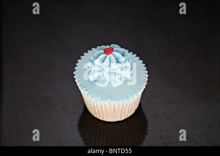 Cupcakes mit blauen Sahnehäubchen auf einer schwarzen Marmor Oberfläche Stockfoto