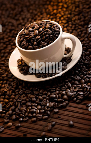 Tasse mit köstlichen gerösteten Kaffeebohnen gefüllt Stockfoto