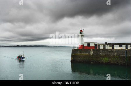 Ein Fischerboot Rückkehr in Newlyn Harbour wie Gewitterwolken aufbauen. Stockfoto