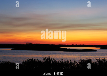 Sonnenuntergang, erfasst über einen Prairie See in Alberta, Kanada.  Es gibt Laub und einer kleinen Insel im Silhouette. Stockfoto