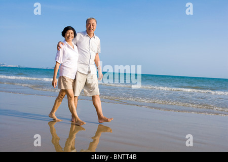 Älteres Paar am Strand entlang spazieren Stockfoto