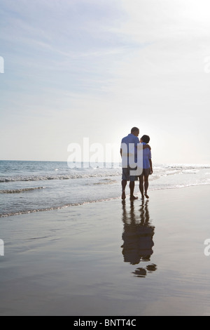 Älteres Paar am Strand entlang spazieren Stockfoto