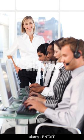 Fröhliche Anführerin mit einem Team auf ein Call-center Stockfoto