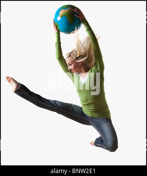 Frau in Luft mit gedrückter Kugel springen Stockfoto