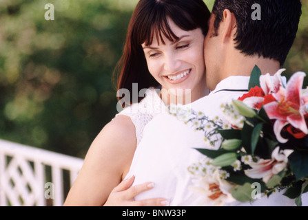 Mann, die Frau zu küssen, während er Blumen hinter seinem Rücken hält. Stockfoto