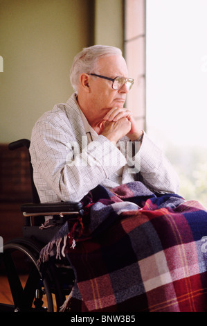 Älterer Mann im Rollstuhl sitzt, während Sie den Blick aus Fenster Stockfoto