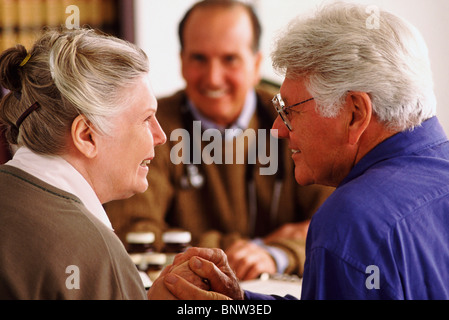 Älteres Paar sitzt am Schreibtisch gegenüber dem Arzt Stockfoto