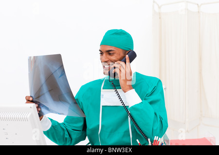 Lächelnde Arzt am Telefon Untersuchung eine Röntgenaufnahme Stockfoto