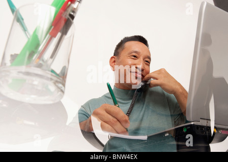 Mann am Telefon sprechen während der Arbeit am laptop Stockfoto