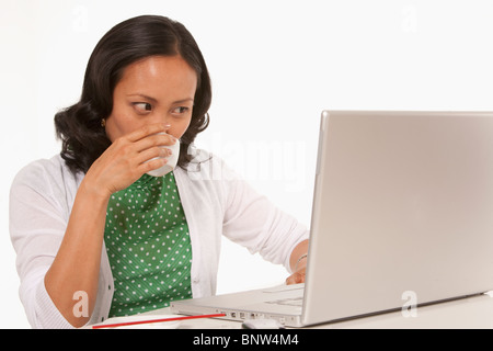 Frau trinkt Kaffee während der Arbeit am laptop Stockfoto
