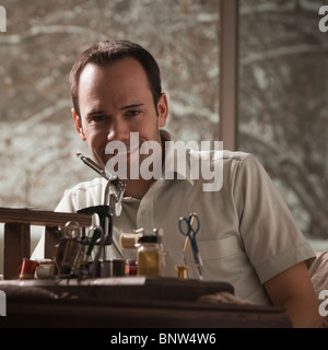 Mann sitzt hinter Reparatur Angelausrüstung Stockfoto