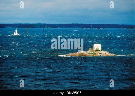 Segelboot, vorbei an kleinen Haus isoliert auf der winzigen Insel im Stockholmer Schären in der Ostsee an windigen Tag Stockfoto