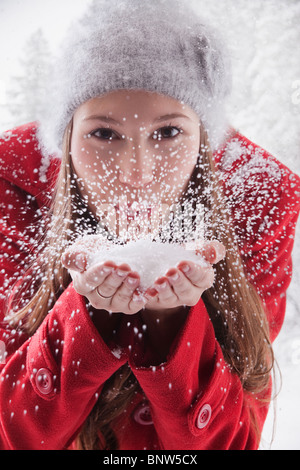 Frau bläst Schnee aus ihren Händen Stockfoto