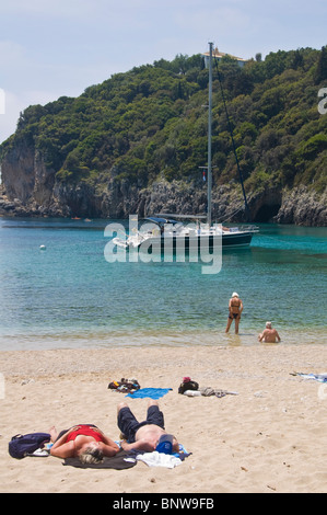 Corfu Beach. Touristen, die auf sandigen Strand bei Paleokastritsa auf der griechischen Insel Korfu Griechenland GR entspannend Stockfoto