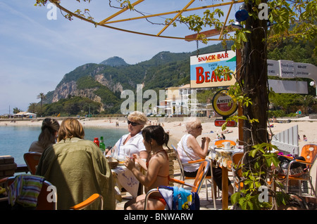 Touristen genießen Mittagessen in der Snackbar am Strand bei Paleokastritsa auf der griechischen Insel Korfu Griechenland GR Stockfoto