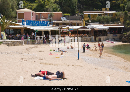 Corfu Beach. Touristen, die auf sandigen Strand bei Paleokastritsa auf der griechischen Insel Korfu Griechenland GR entspannend Stockfoto