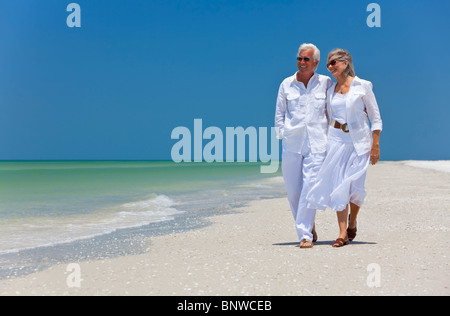 Romantische senior Mann und Frau Brautpaar zu Fuß auf einem einsamen tropischen Strand mit hellen klaren blauen Himmel Stockfoto