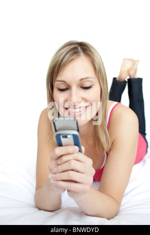 Helle Frau eine SMS auf einem Bett liegend Stockfoto