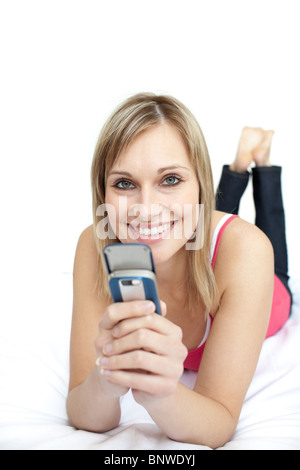 Freuen uns Frau eine SMS auf einem Bett liegend Stockfoto