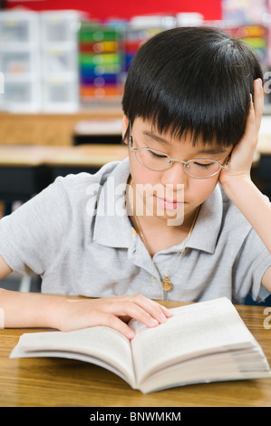 Grundschule Schüler lesen Buch am Schreibtisch Stockfoto