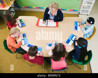 Kindergarten-Schüler mit ihrem Lehrer am Tisch sitzen Stockfoto