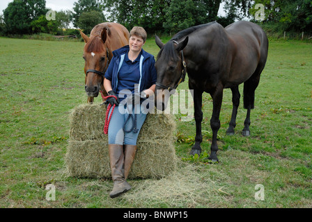 Sarah Phillips mit "Ernie" und "Kenny" neben Heu an Pipers Hill Farm in Bischöfe Itchington, Warwickshire Stockfoto