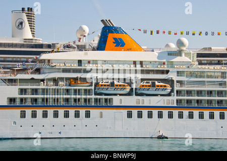 EUROPA Tourist Kreuzfahrtschiff mit Rumpf gemalt von zwei Männern im Schlauchboot Beiboot im Hafen auf der griechischen Insel Korfu Griechenland GR Stockfoto