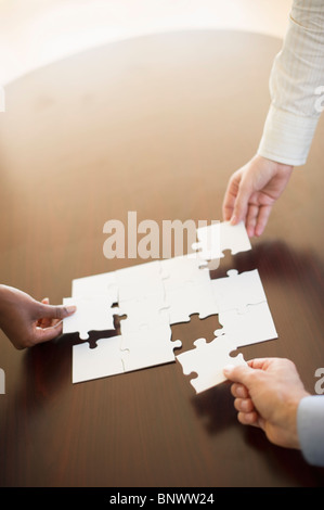 Hände, die Puzzle zusammenfügen Stockfoto