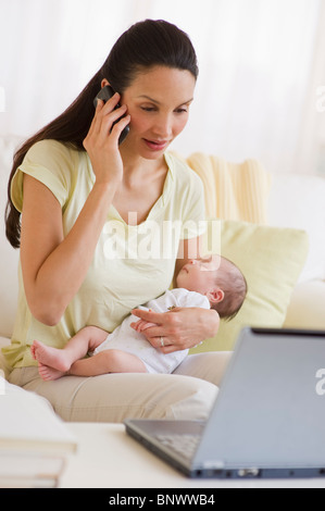 Mutter am Telefon sprechen, halten Sie ihr baby Stockfoto