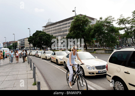 Frau mit Fahrrad vorbei an einem Taxistand am Karlsplatz Stachus München Stockfoto