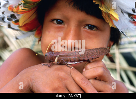 Young Urueu-Wau-Wau Indianer mit großen Heuschrecke Stockfoto