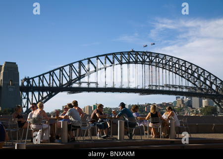 Menschen genießen Sie einen Drink an der Bar Opera mit der Sydney Harbour Bridge im Hintergrund. Sydney, New South Wales, Australien Stockfoto