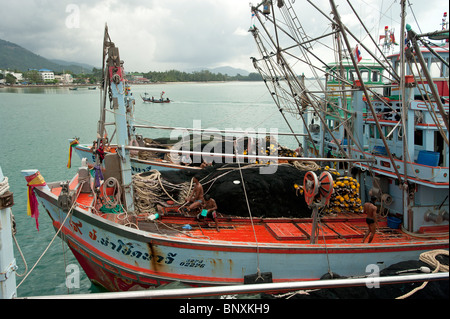 Thai Fischerboot in Nathon Hafen kommen auf Koh Samui Thailand gesehen durch die Takelage eines festgemachten Fischerbootes Stockfoto