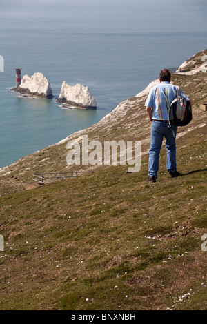 Mann, der im April auf der Isle of Wight, Hampshire, England, in Richtung Needles geht - Leuchtturm von Needles und Felskreide-Stapelformation Stockfoto