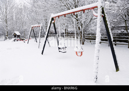 Ein Kinderspielplatz im Dorf unter einer Schneedecke. Wrington, Somerset, England. Stockfoto