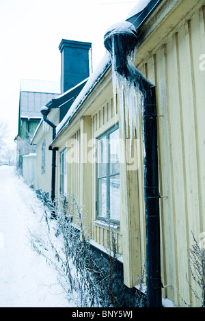 Eiszapfen hängen von Dachrinne am Haus Stockfoto