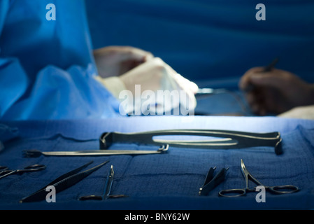 Chirurgische Instrumente, aufgereiht auf Tablett, Chirurgen, die im Hintergrund tätig Stockfoto