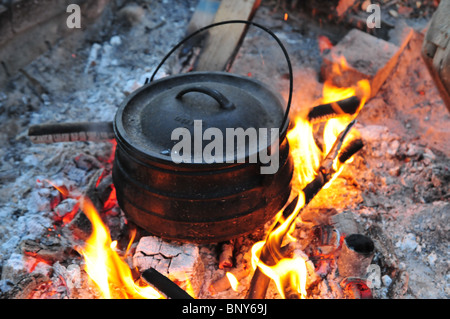 Kochen auf offenem Feuer, eine eiserne Kessel auf ein Outdoor-Holz-Feuer Hand rühren die Brühe Stockfoto