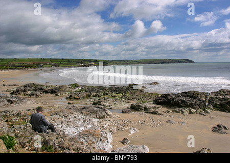 Waterford, Irland Clonea Strand, ein älterer Mann saß auf Felsen Stockfoto