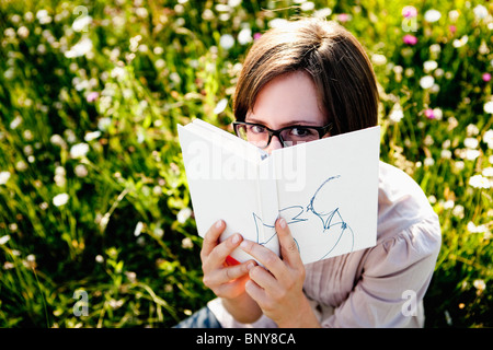 Frau versteckt sich hinter Buch Stockfoto