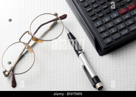 Gläser, Taschenrechner und Bleistift auf ein offenes notebook Stockfoto