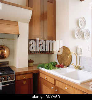 Weiße Wanne mit Messing Wasserhahn in moderne weiße Küche mit hellen Holz ausgestattete Einbauschränke Stockfoto