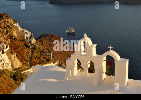 Glockenturm der Kirche mit einem Segelschiff in der Caldera in Oia auf der griechischen Insel Santorini in den Kykladen Stockfoto