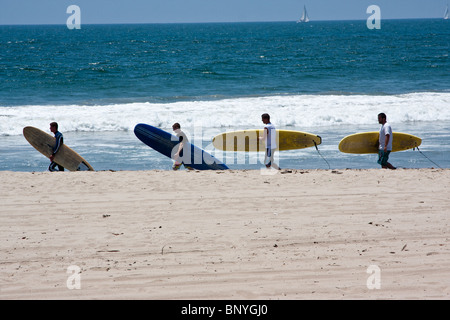 Vier Surfer gehen im Einklang mit ihren Brettern am Venice Beach, Kalifornien, USA Stockfoto